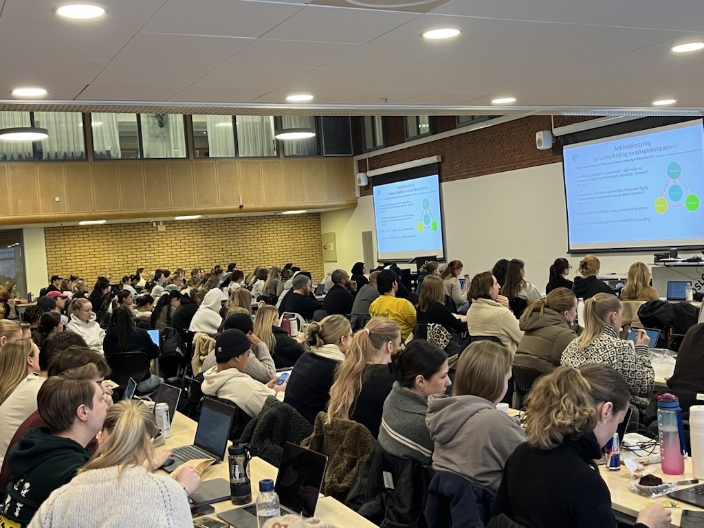 En gruppe mennesker som sitter i et rom og ser på en skjerm