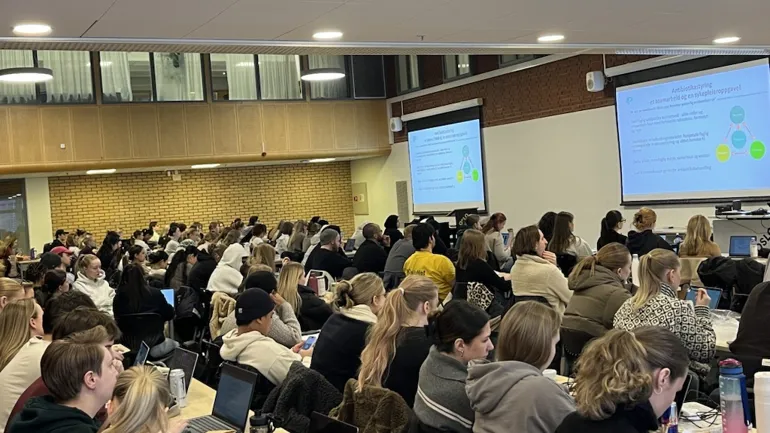 En gruppe mennesker som sitter i et rom og ser på en skjerm