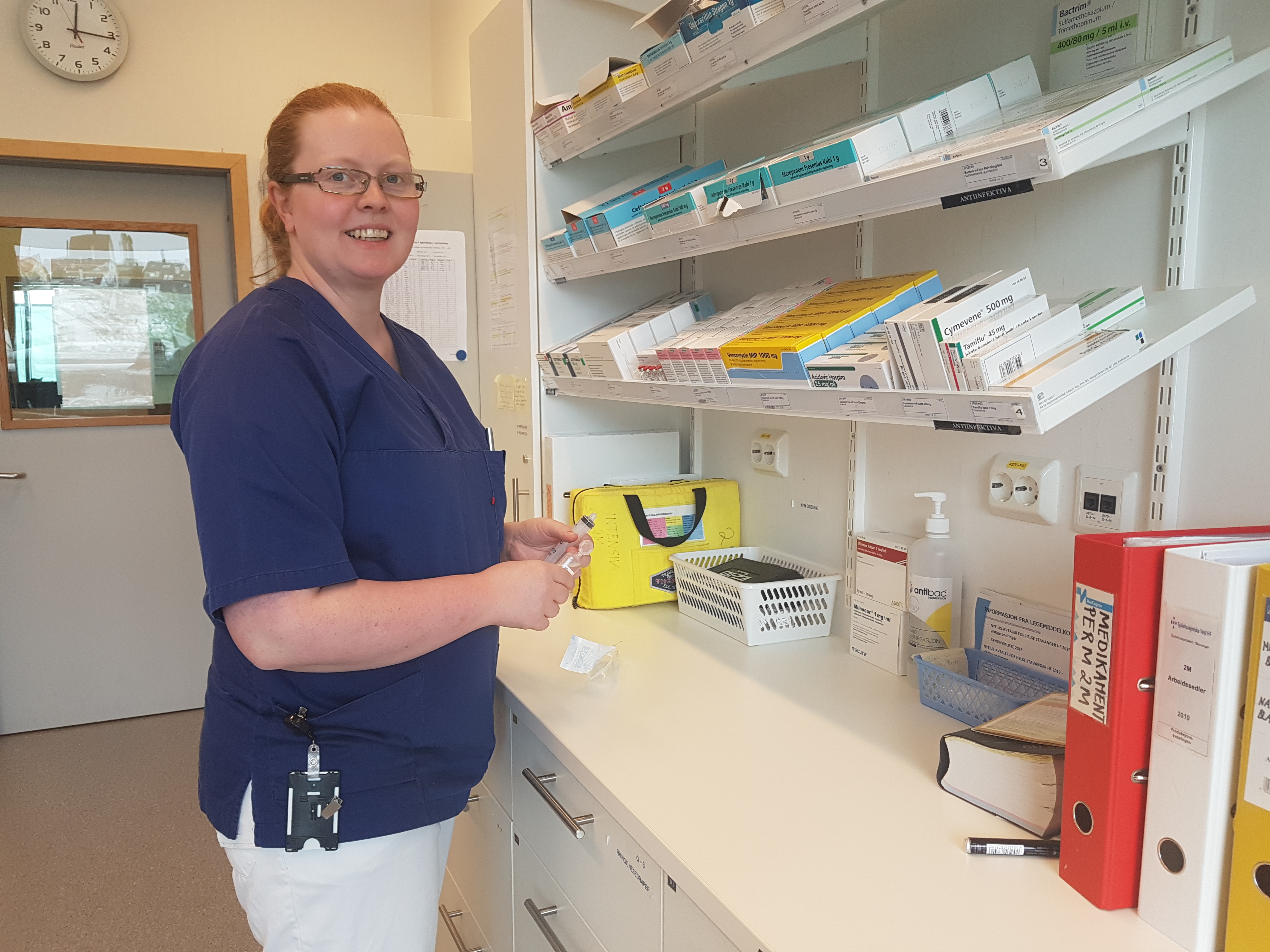 Kvinnelig helsepersonell står på medisinrom