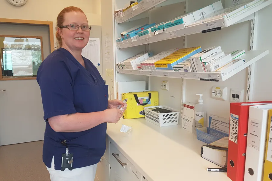 Kvinnelig helsepersonell står på medisinrom