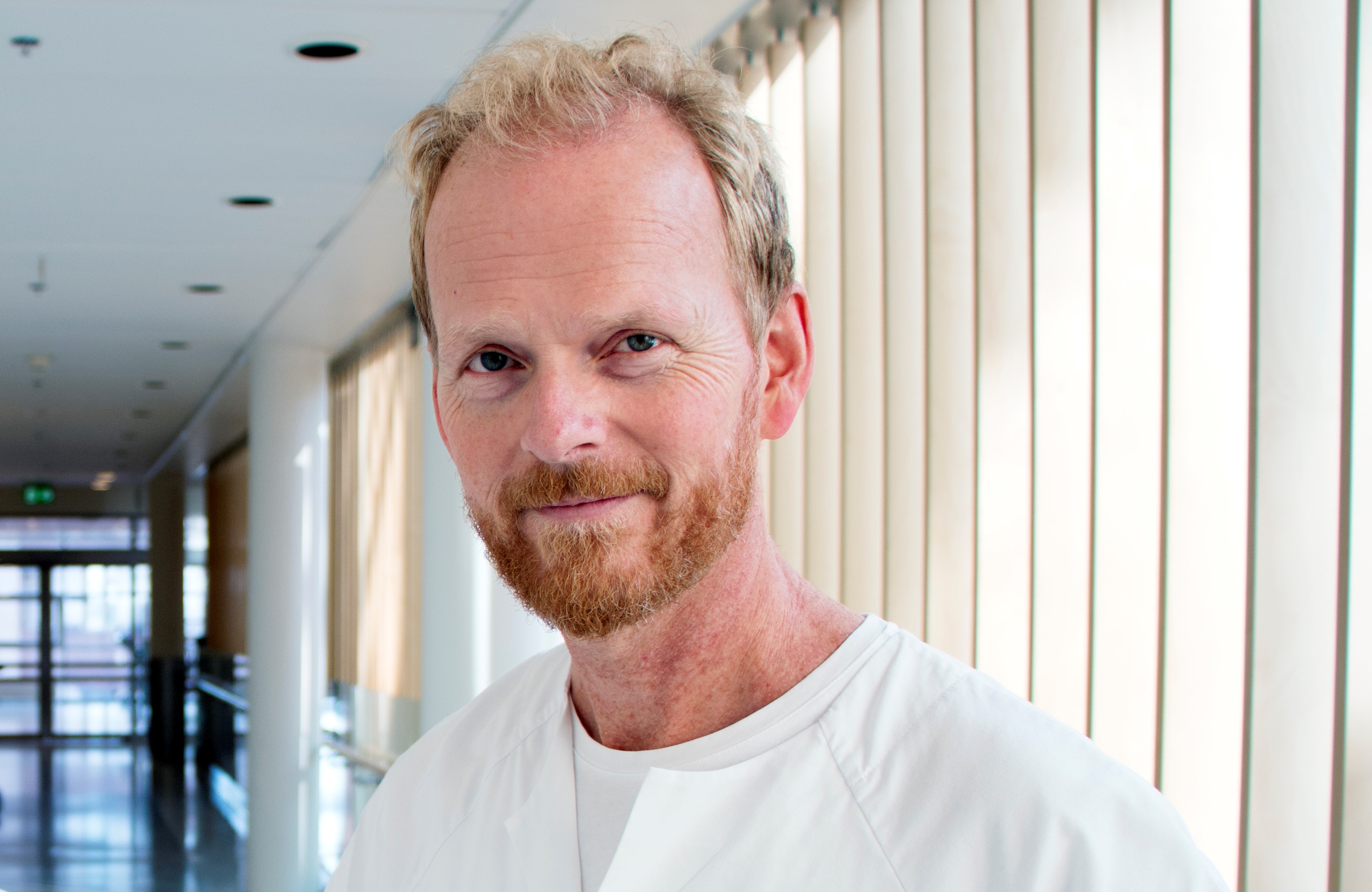 En mann med skjegg i en sykehuskorridor