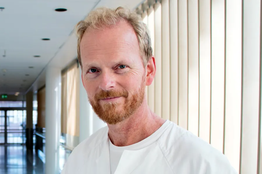 En mann med skjegg i en sykehuskorridor