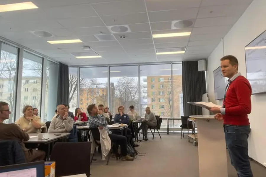 En person som står foran en gruppe mennesker som sitter ved bord