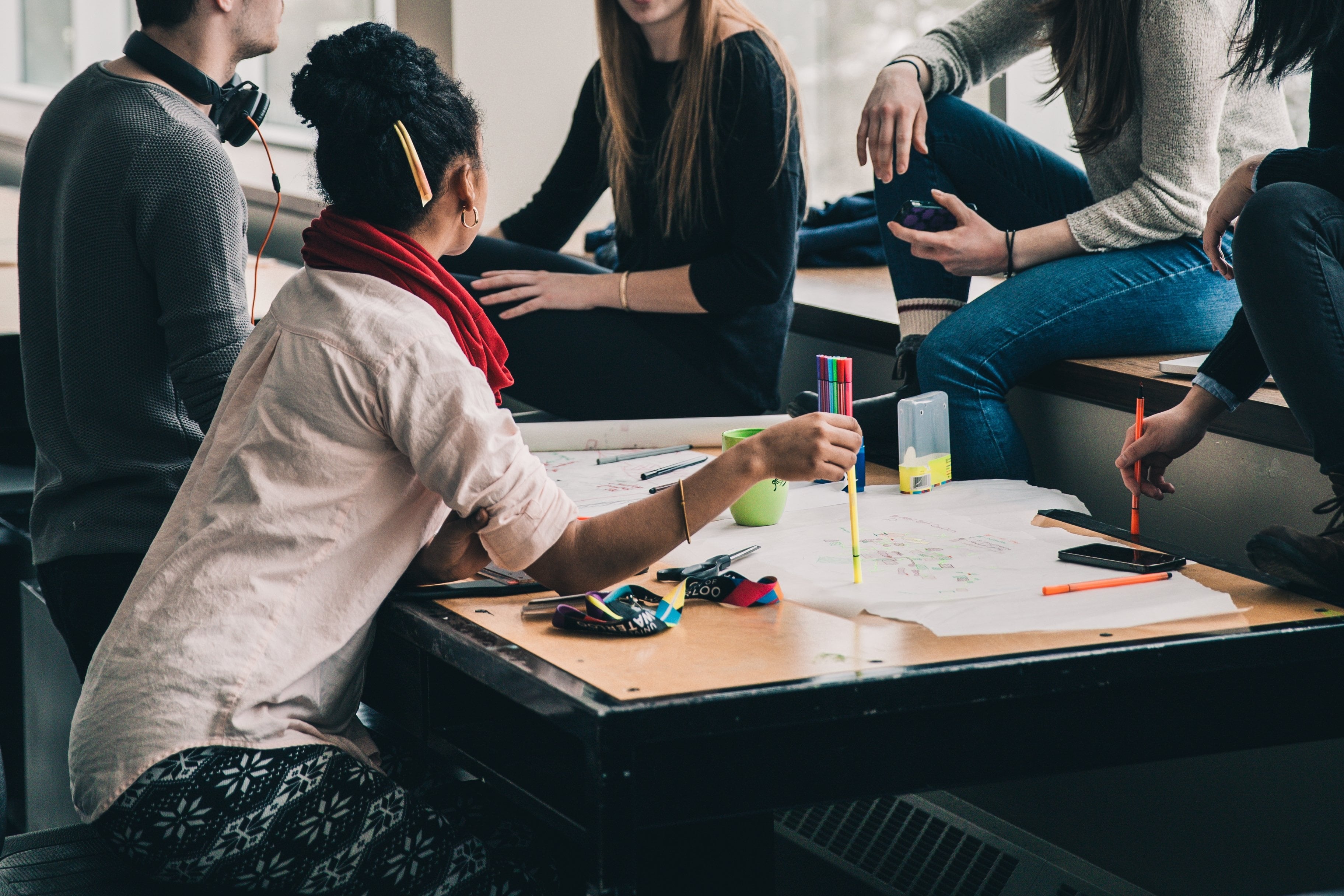 En gruppe studenter som sitter ved pulter og diskuterer