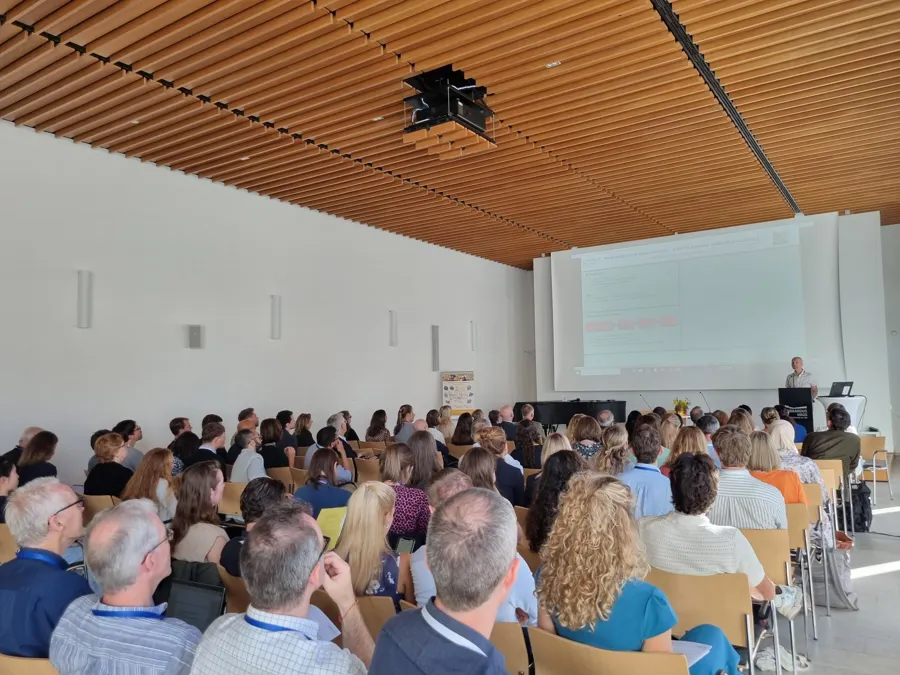 En gruppe mennesker som sitter i et rom med en projektorskjerm