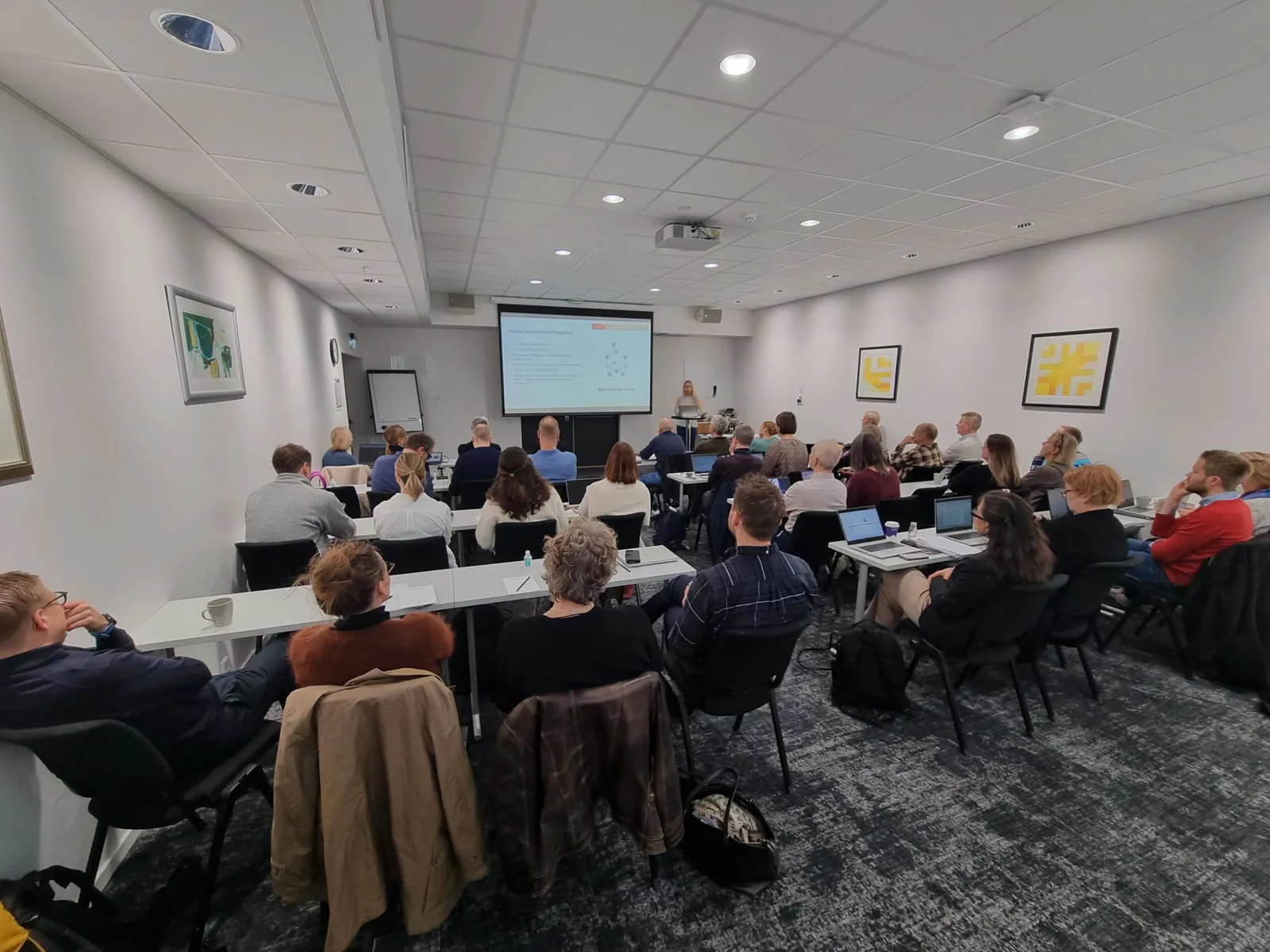 En gruppe mennesker som sitter i et rom og ser på en skjerm